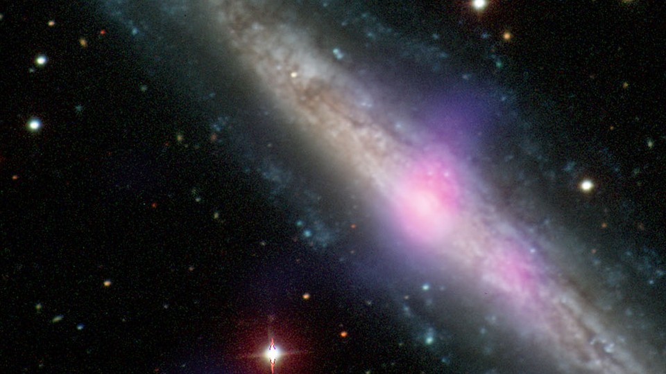 A galaxy with an active galactic nucleus is seen in this image, which combines data from the Carnegie-Irvine Galaxy Survey in the optical range and NuSTAR in the X-ray range. 