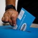 A man's hand is pictured dropping his vote into a ballot box in an Israeli general election.
