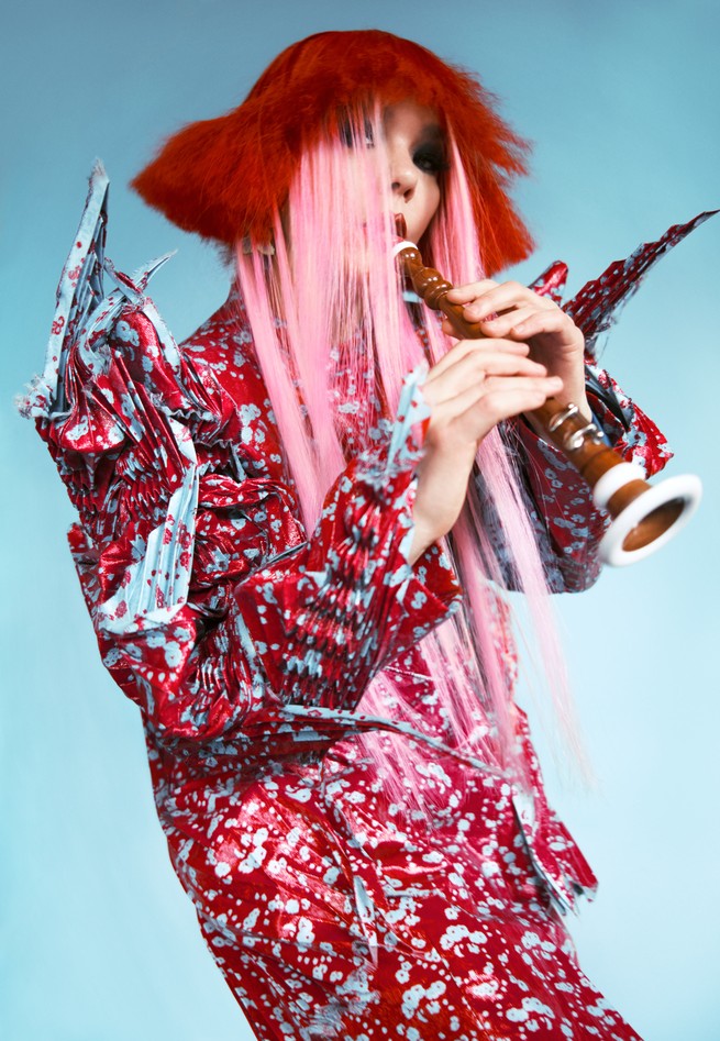 Bjork with red and pink hair, playing a clarinet