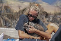 A woman cradles her cat after finding him in the aftermath of a wildfire.