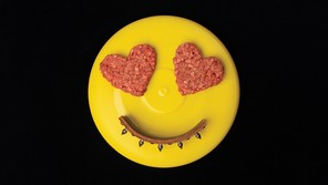 photo of yellow frisbee with 2 heart-shaped ground-beef patties as eyes and arc of dog collar as smile