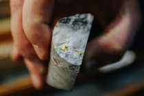 Rise Gold CEO Benjamin Mossman holds a section of core sample containing chunks of gold.