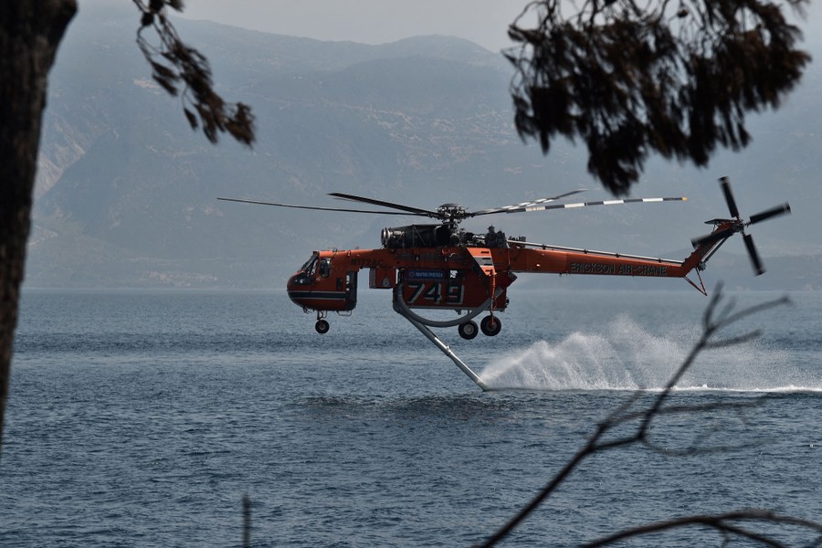 A firefighting helicopter splashes its hose into the ocean.