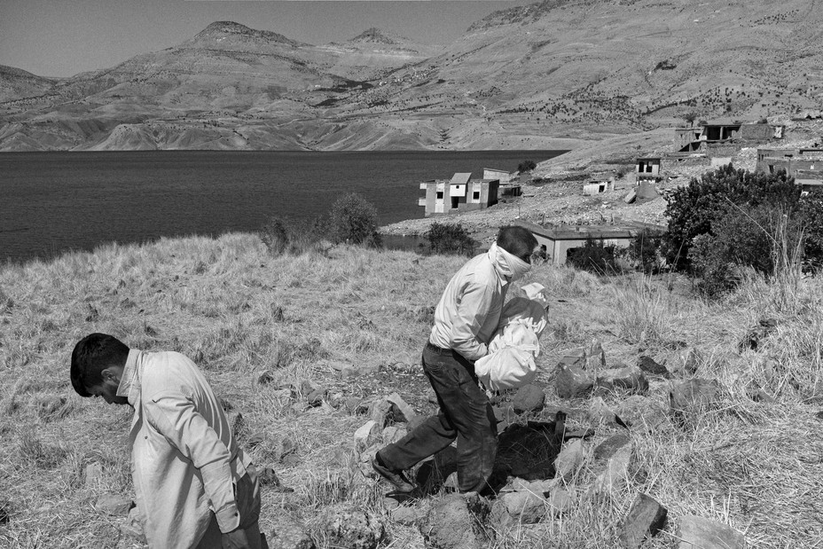 Picture of people removing the bodies of their loved ones and relatives from the village cemetary as water levels rise at Ilisu Dam reservoir lake in Sirnak, Turkey.