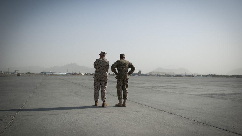 Generals John Allen and David Petraeus stand at an airfield in Afghanistan