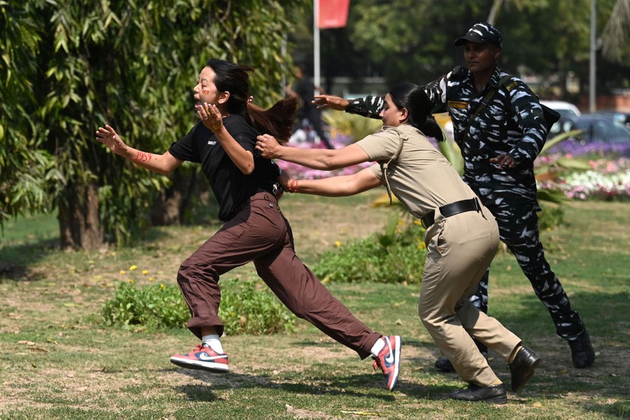 Two police officers chase a protester who runs.