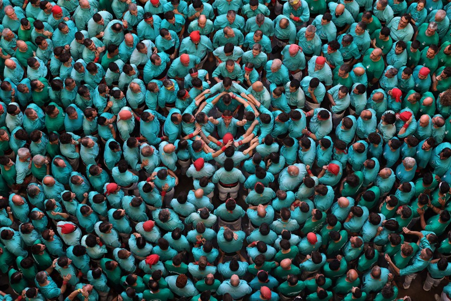 An overhead view of many people wearing green shirts crowding around around a person in the center