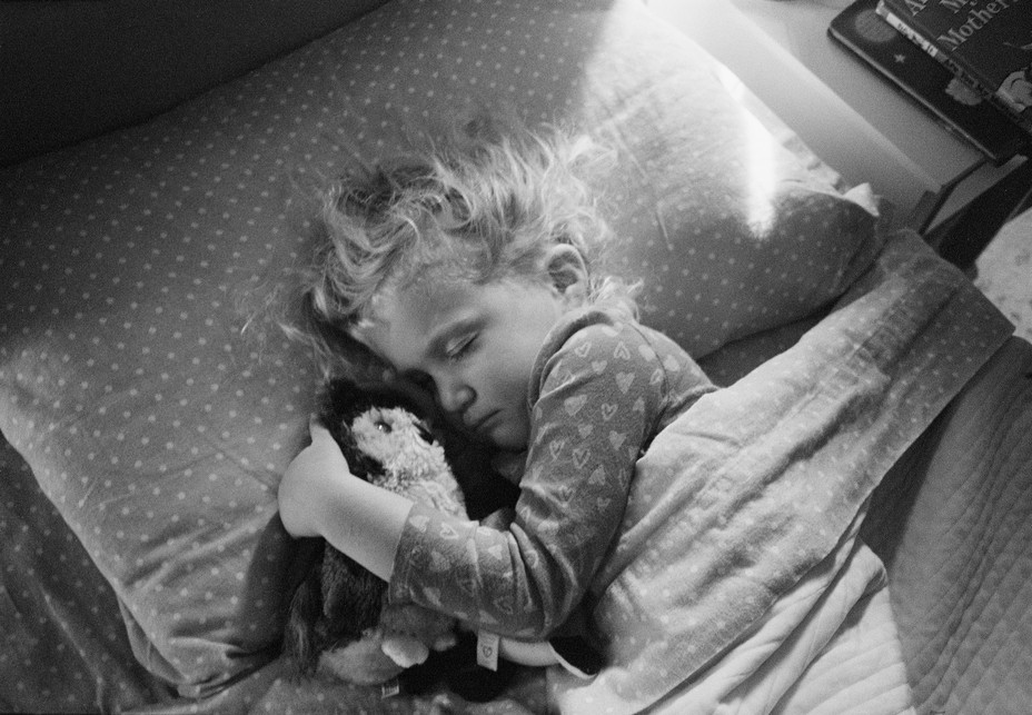 a child clutches a stuffed owl in her bed