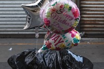 Balloons with the words Happy Mother's Day are on the ground stuff in a trash bag