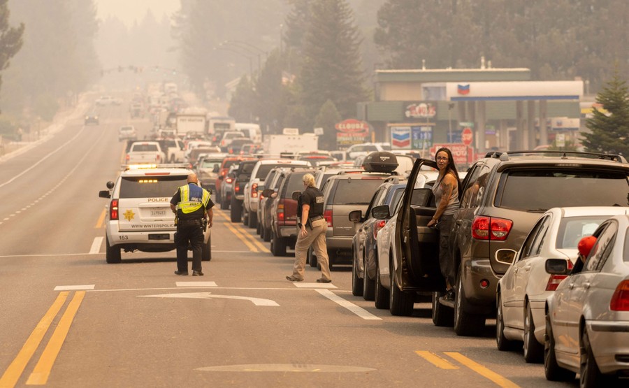 A long line of vehicles sit stuck in traffic beneath a smoky sky.