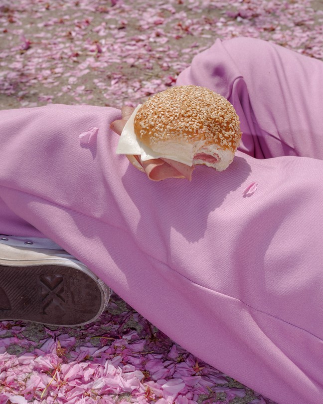 a sandwich sitting on the leg of someone wearing pink sweatpants