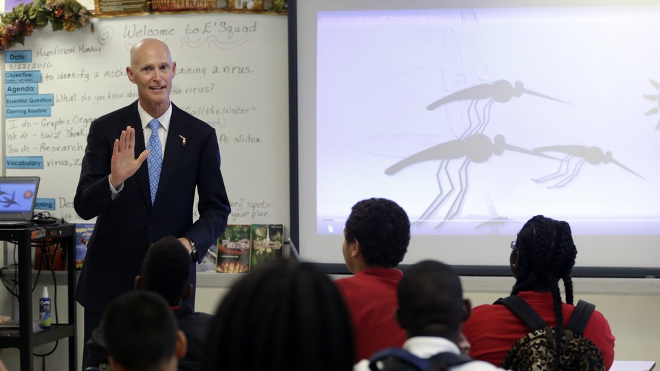 Florida Governor Rick Scott talks with students who are studying the Zika virus, while visiting a classroom on the first day of school, at the Jose de Diego Middle School, on August 22, 2016.