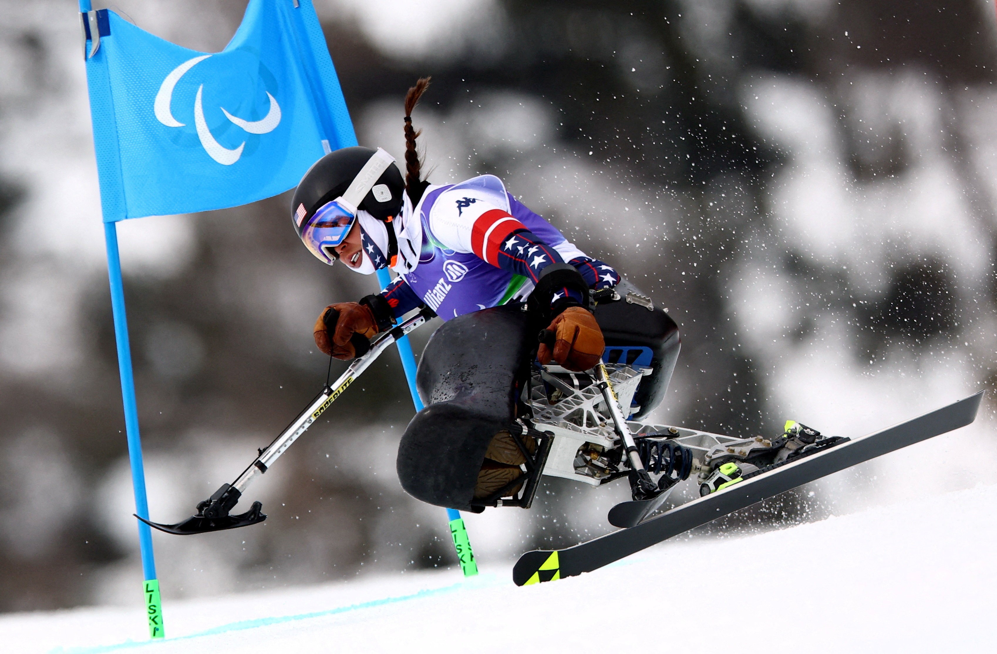 A seated para-Alpine racer skis down a course.