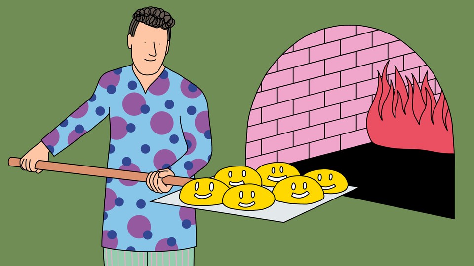 A baker loads a batch of bread-dough-shaped smiley faces into a brick oven.