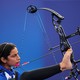 A para-archer draws back an arrow, holding her bow with her right foot.