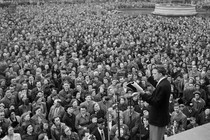 Evangelist Billy Graham, on stage, addresses a crowd.