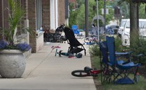 Abandoned lawn chairs and kid's bikes stand at the scene of a Fourth of July parade shooting
