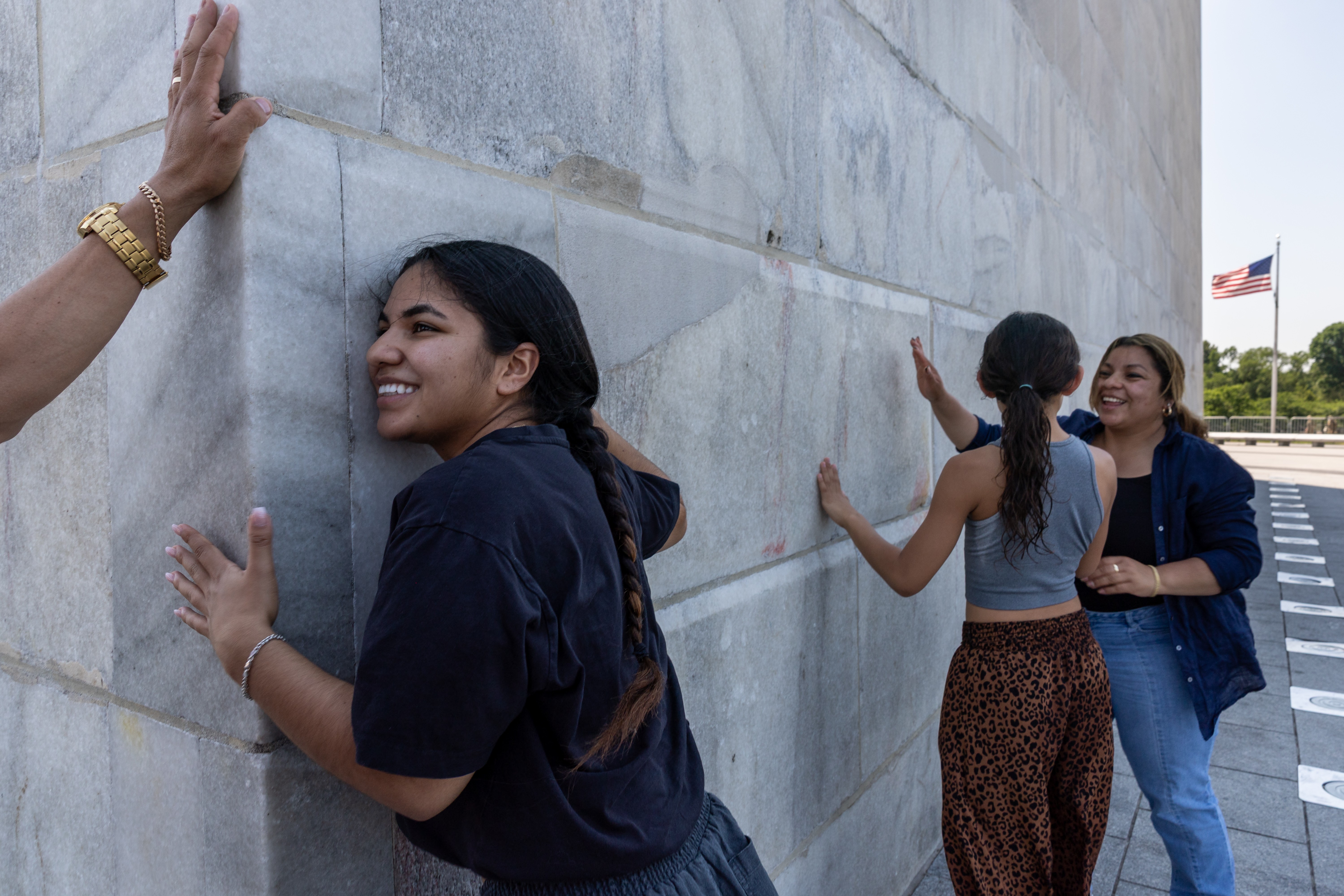 Several people lean against the base of the Washington Monument.