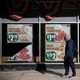 a man walks in front of posters advertising food