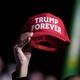 A Trump supporter holds up a red baseball cap that reads: Trump Forever