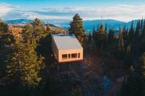 An unfinished house with a slanted roof on a mountain among trees