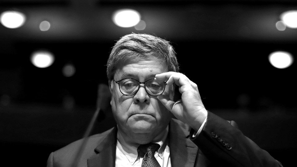 Shown in black and white, outgoing Attorney General Bill Barr adjusts his glasses while seated before a microphone