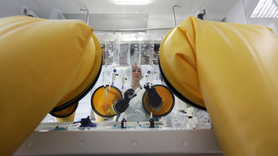 A dispensing chemist prepares drugs for a chemotherapy treatment in a sterile room.