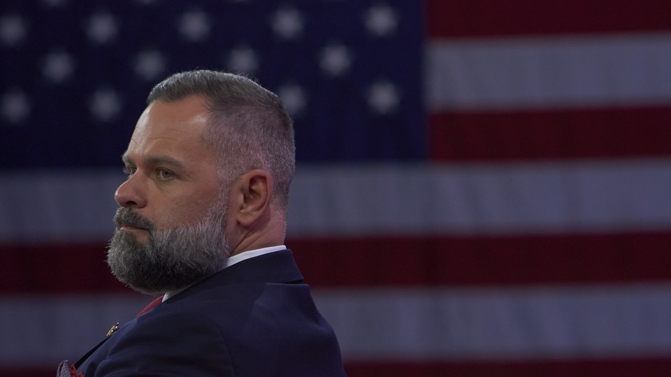 Rep. Cory Mills sits in front of a large American flag