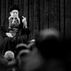 Iran's Supreme Leader Ali Khamenei speaks on a stage, gesturing with his left hand.