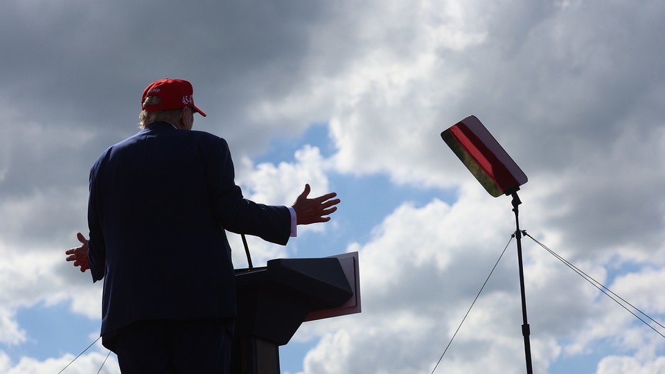 A photo of Trump speaking at a podium with the sky filling the frame