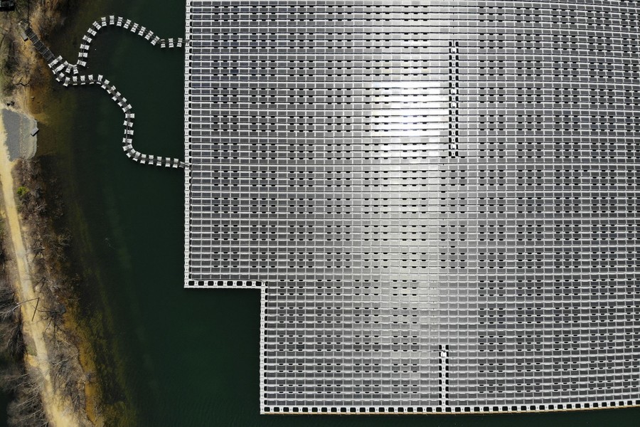 An aerial view of a large array of solar panels floating on a reservoir