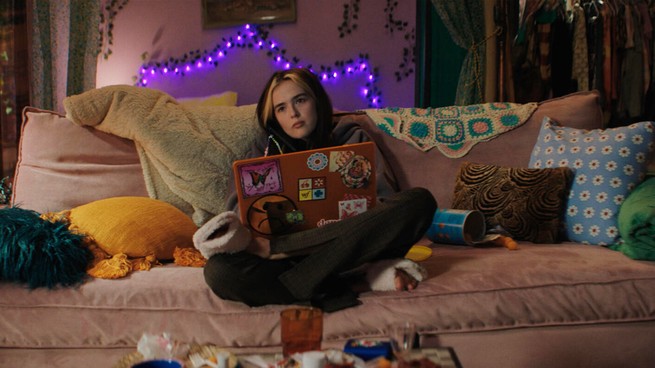 Zoey Deutch sitting on a couch with a laptop in 'Not Okay'