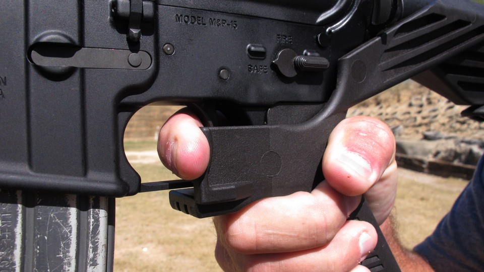 A shooting instructor illustrates the grip on an AR-15 rifle fitted with a "bump stock" at a gun club.