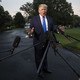 President Donald Trump speaks into press microphones on a White House driveway.