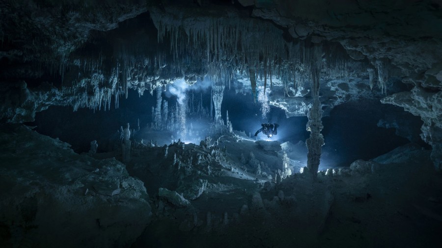 A diver swims through an underwater cave.
