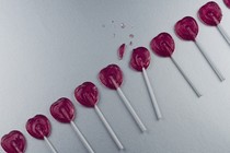 a photo of heart-shaped lollipops in a row, with one that's broken in the middle