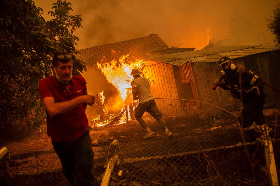 A firefighter and locals rush toward a burning house.
