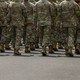 Members of the armed forces march forward, the back of their heads just barely out of frame
