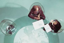 Corporate people sit at a desk, looking at papers together