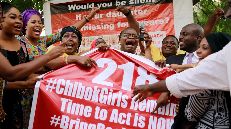 Members of the #BringBackOurGirls (#BBOG) campaign react on the presentation of a banner which shows "218", instead of the previous "219", referring to kidnapped Chibok school girls, during a sit-out in Abuja, Nigeria May 18, 2016, after receiving news that a Nigerian teenager kidnapped by Boko Haram from her school in Chibok more than two years ago has been rescued.