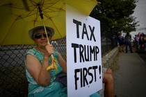 A woman holds a sign during demonstrations as U.S. President Donald Trump delivers a speech on tax reform.