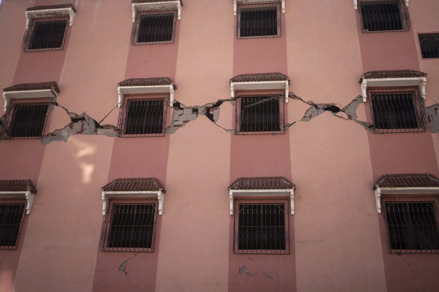 The facade of a tall building, criss-crossed with deep cracks, following an earthquake