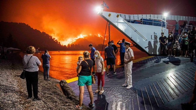 People board a ferry prior to an evacuation as a wildfire approaches the seaside village of Limni, on the island of Evia, Greece, on August 6, 2021.