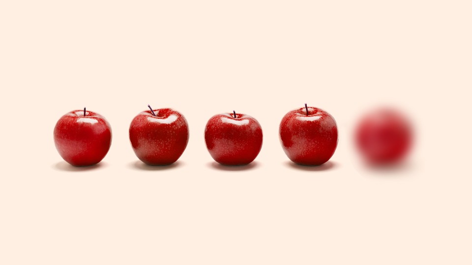 Five apples in a line, but the furthest one on the right is blurry