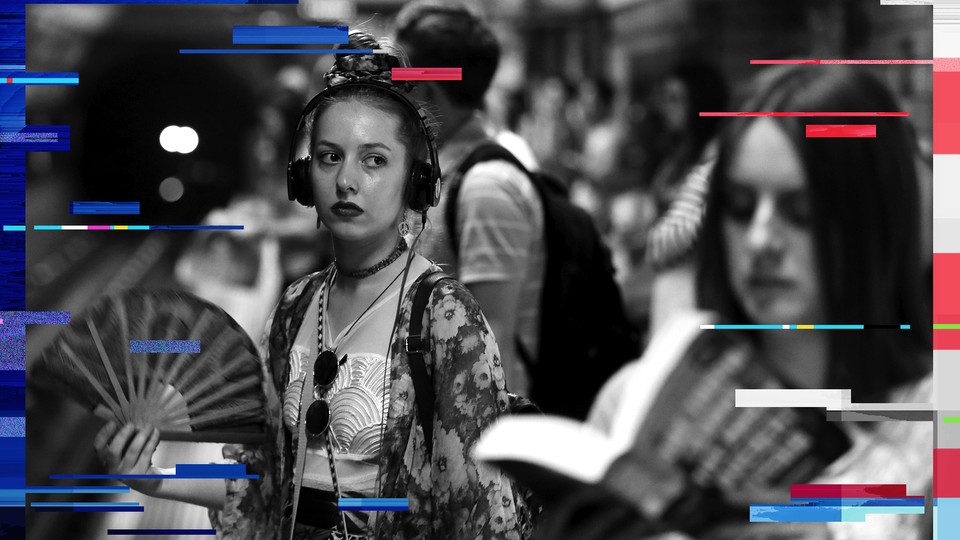 A woman wearing headphones fans herself while waiting for a train on the London underground in July 2015. 