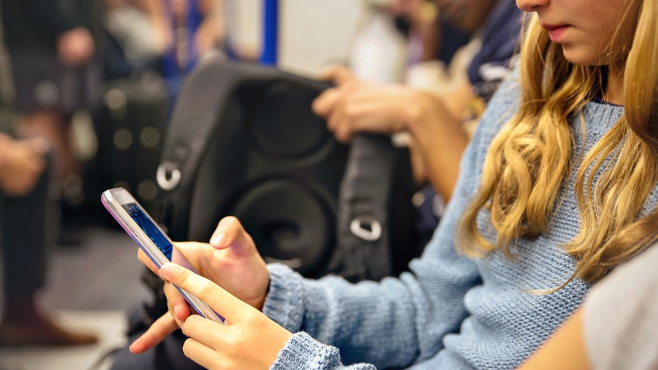 A teenager uses an iPhone while riding on public transit.