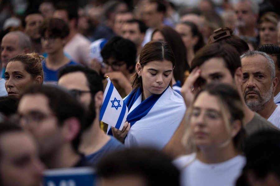 A crowd of people, one holding a small Israeli flag