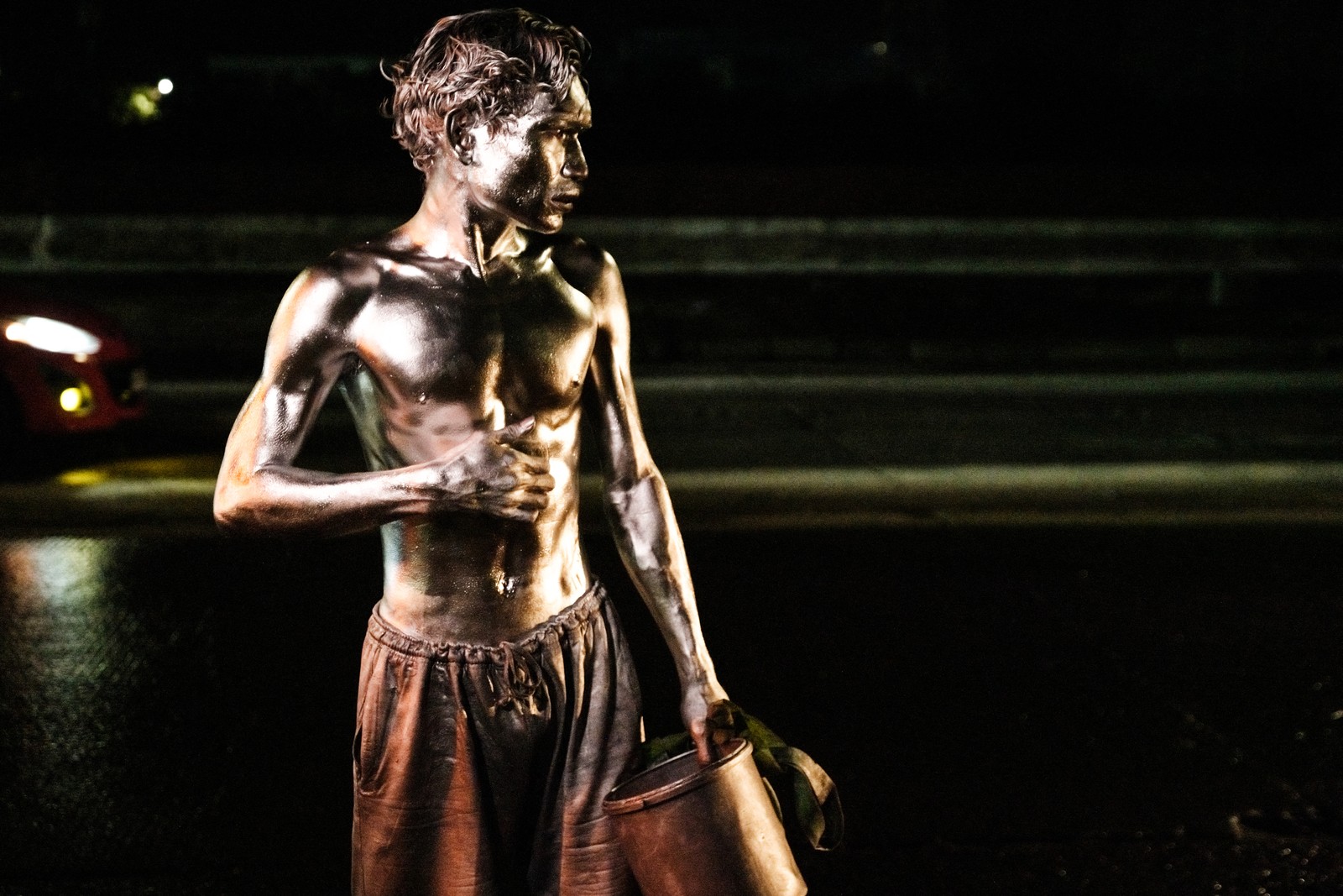 A close view of a shirtless street performer covered in silver paint