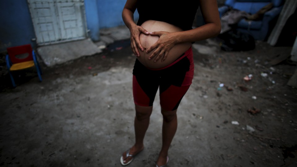 A pregnant woman stands outside her house in Recife, Brazil in February 2016.