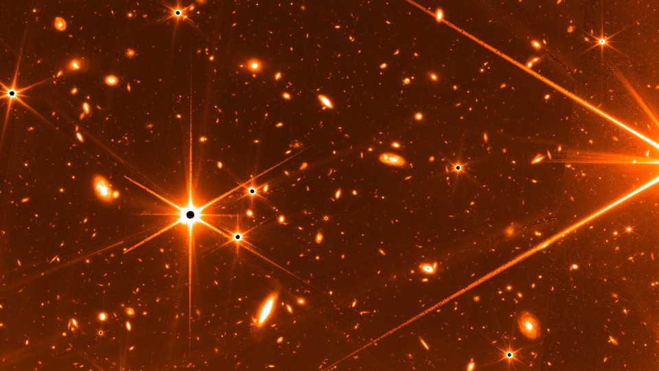 A test image taken by the James Webb Space Telescope that shows a few bright stars and many galaxies in the background